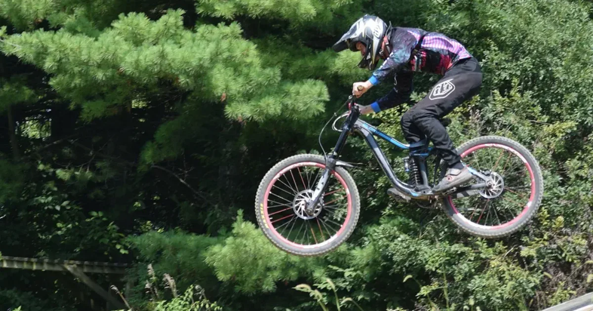 Rowerzysta MTB w pełnym kasku w skoku w bike parku