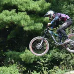 Rowerzysta MTB w pełnym kasku w skoku w bike parku