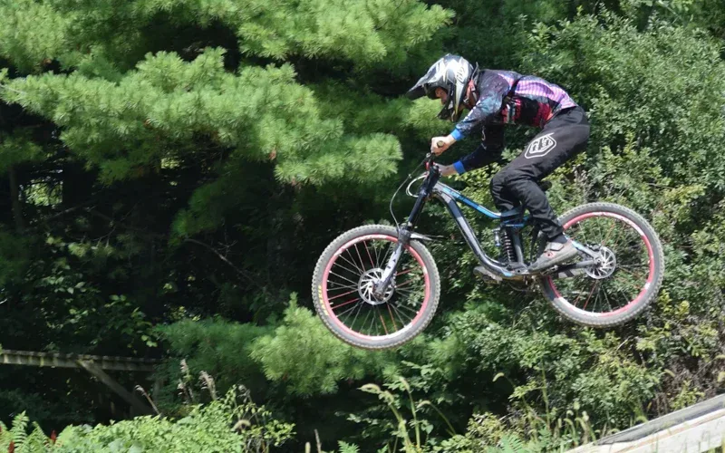 Rowerzysta MTB w pełnym kasku w skoku w bike parku
