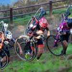 Trzy zawodniczki cyclocross niesa rowery na ramionach pod gore w trakcie wyscigu