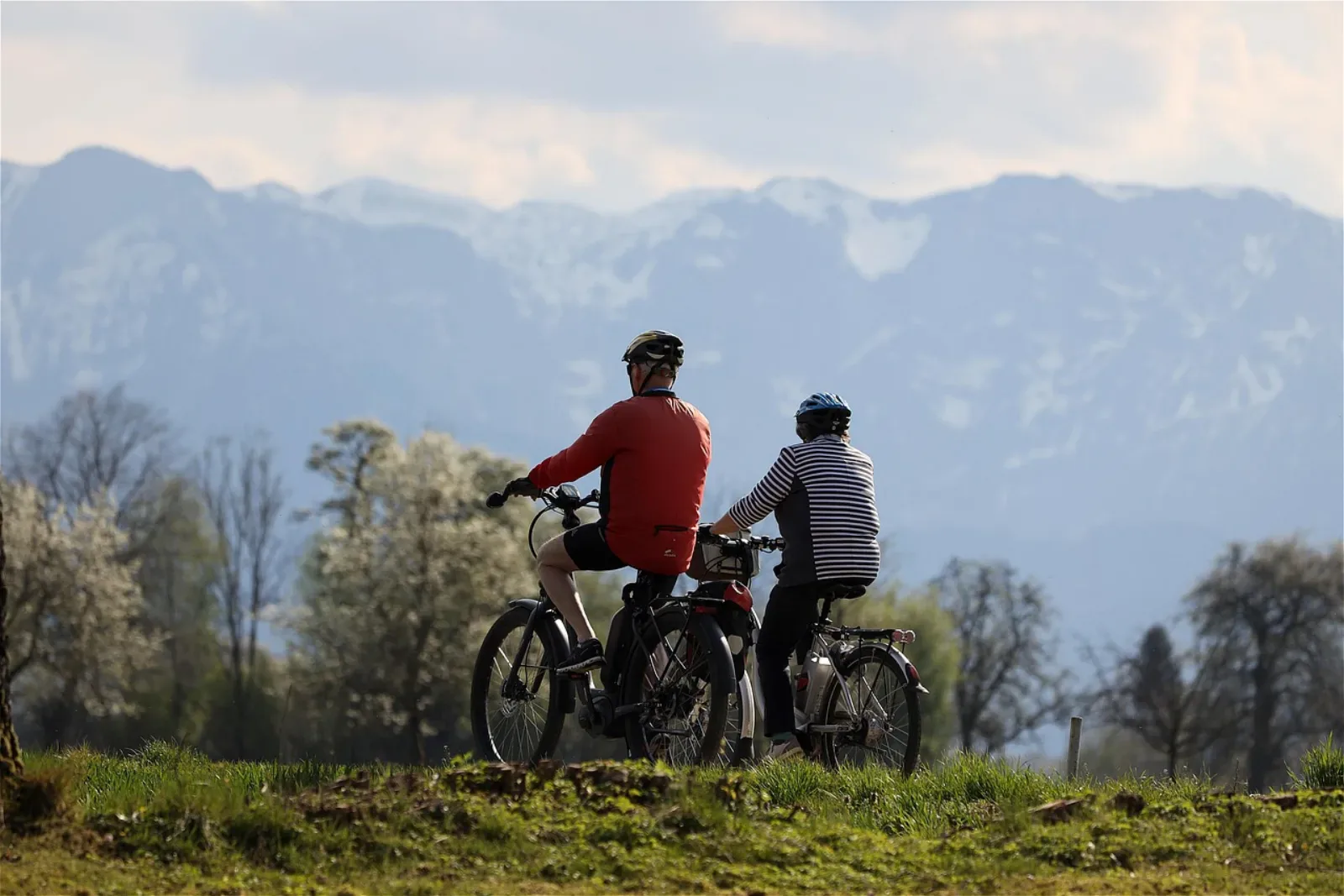 Para rowerzystów na e-bikach na trasie z widokiem na ośnieżone szczyty alpejskie