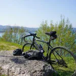 Czarny rower gravel z bidonem na skałce nad jeziorem