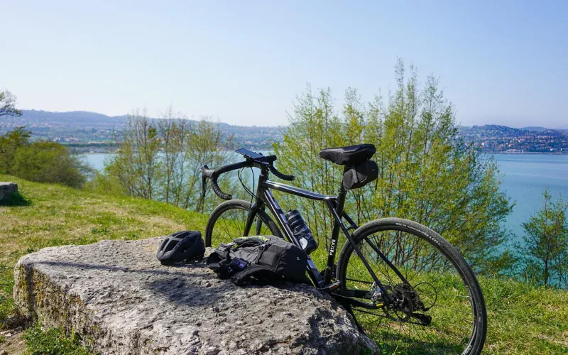 Czarny rower gravel z bidonem na skałce nad jeziorem