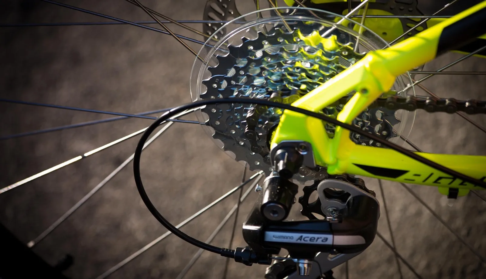 Kaseta MTB i tylna przerzutka Shimano Acera close-up — żółta rama, koło z szprychami, łańcuch