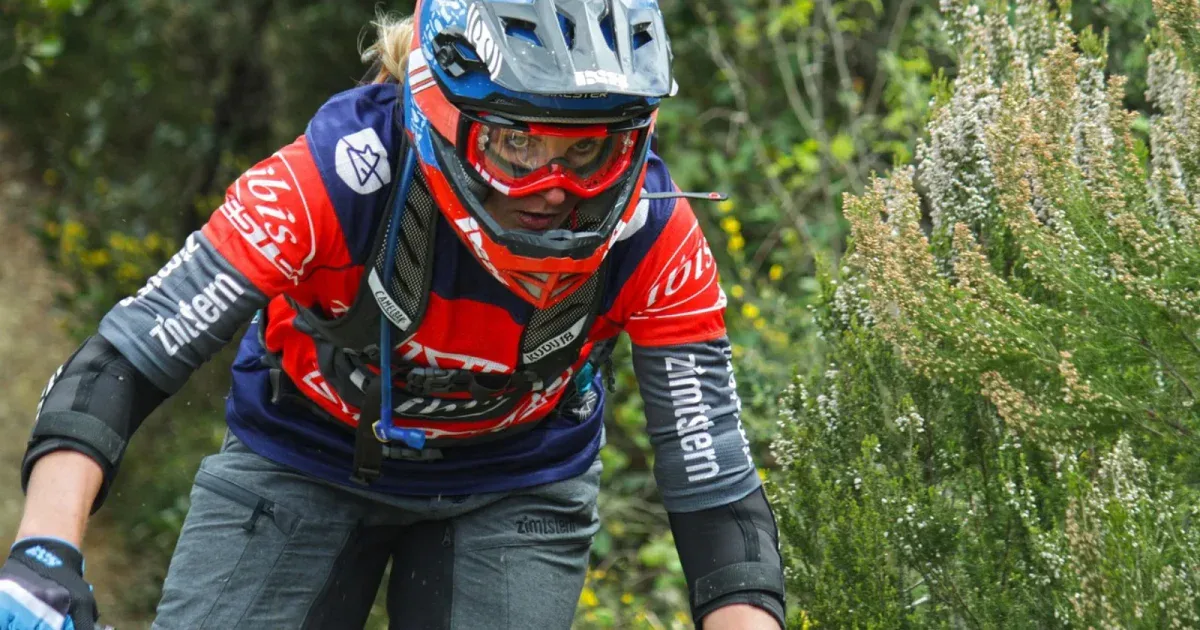 Kobieta na rowerze MTB w pełnym kasku enduro, koncentracja podczas zjazdu