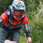 Kobieta na rowerze MTB w pełnym kasku enduro, koncentracja podczas zjazdu