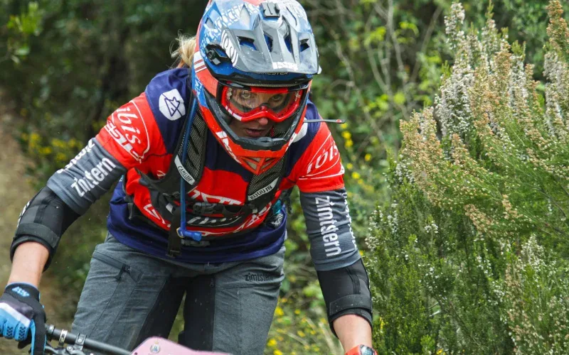 Kobieta na rowerze MTB w pełnym kasku enduro, koncentracja podczas zjazdu