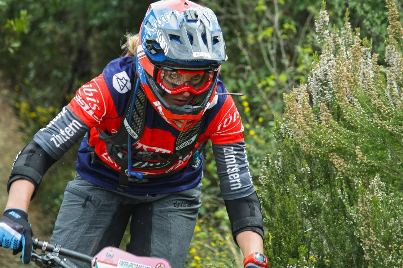 Kobieta na rowerze MTB w pełnym kasku enduro, koncentracja podczas zjazdu
