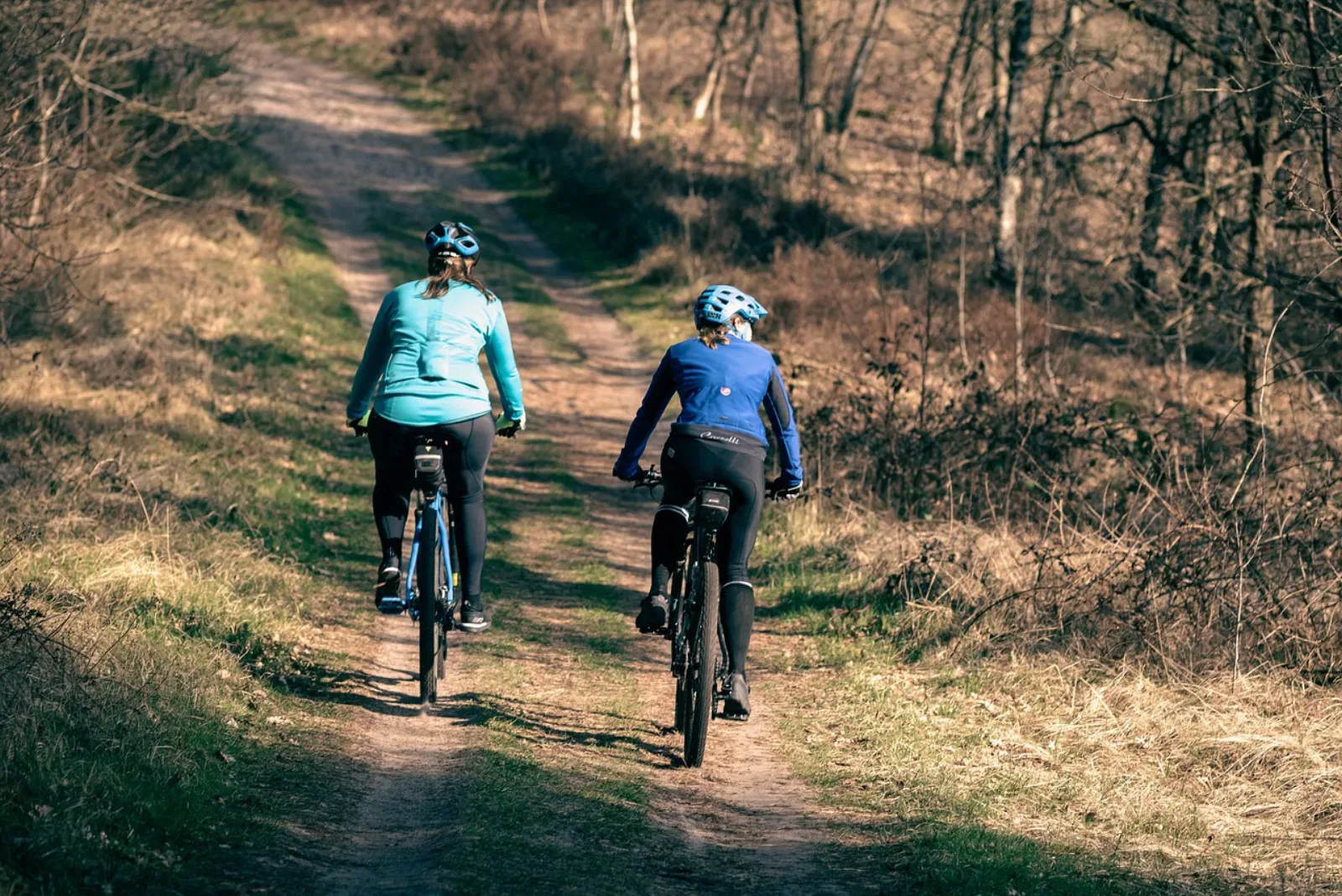 Dwie kobiety na hardtailach MTB jadą leśną ścieżką jesienią