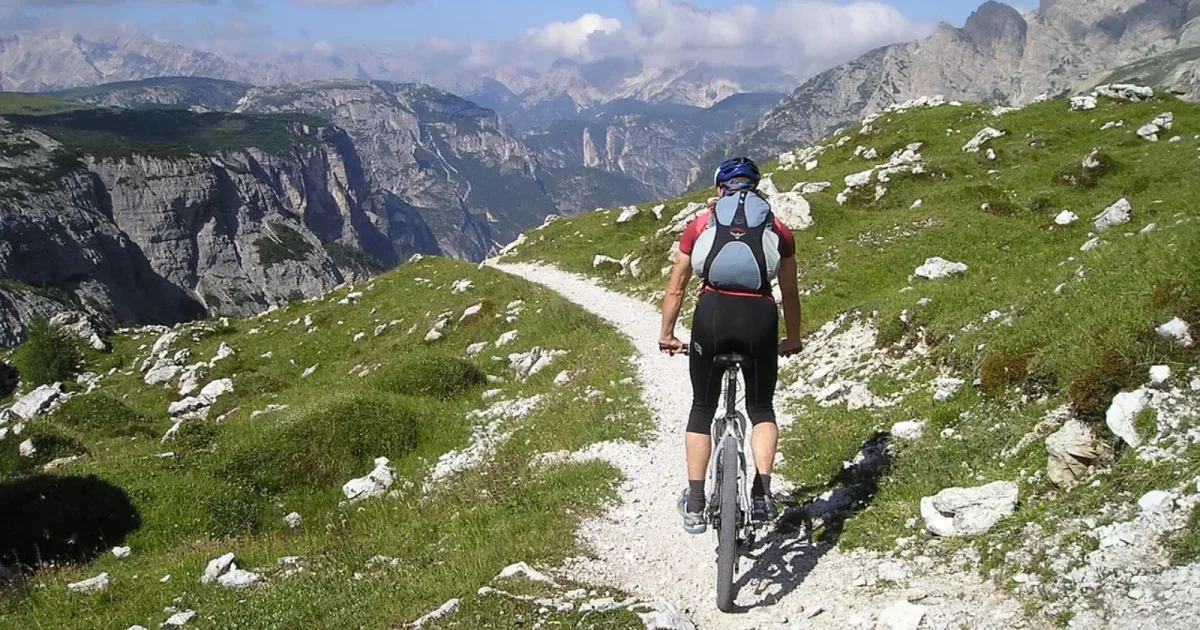 Rowerzysta MTB z plecakiem hydracyjnym jadący kamienistą ścieżką w Dolomitach