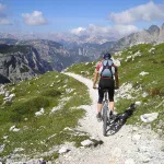 Rowerzysta MTB z plecakiem hydracyjnym jadący kamienistą ścieżką w Dolomitach