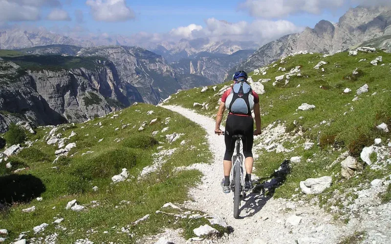 Rowerzysta MTB z plecakiem hydracyjnym jadący kamienistą ścieżką w Dolomitach
