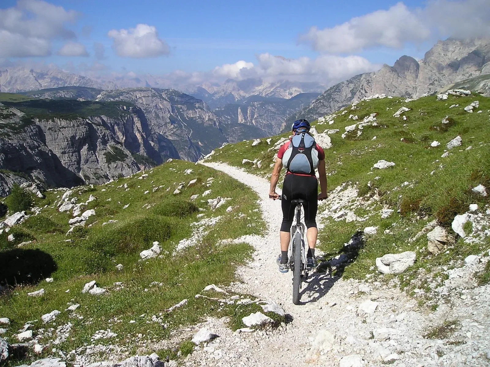 Rowerzysta MTB z plecakiem hydracyjnym jadący kamienistą ścieżką w Dolomitach