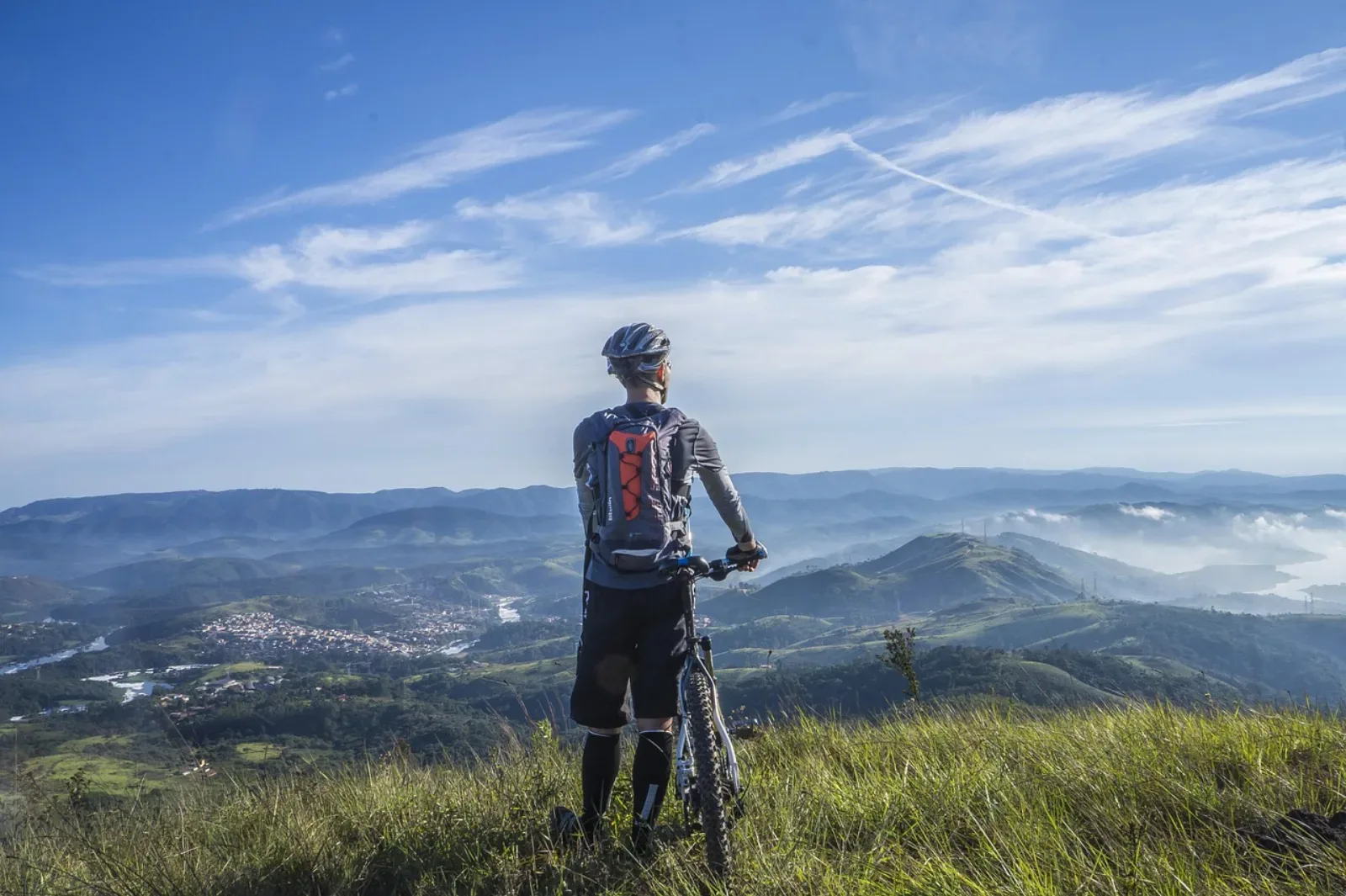 Rowerzysta MTB stoi z rowerem i patrzy na panoramę gór — moment przerwy na trasie