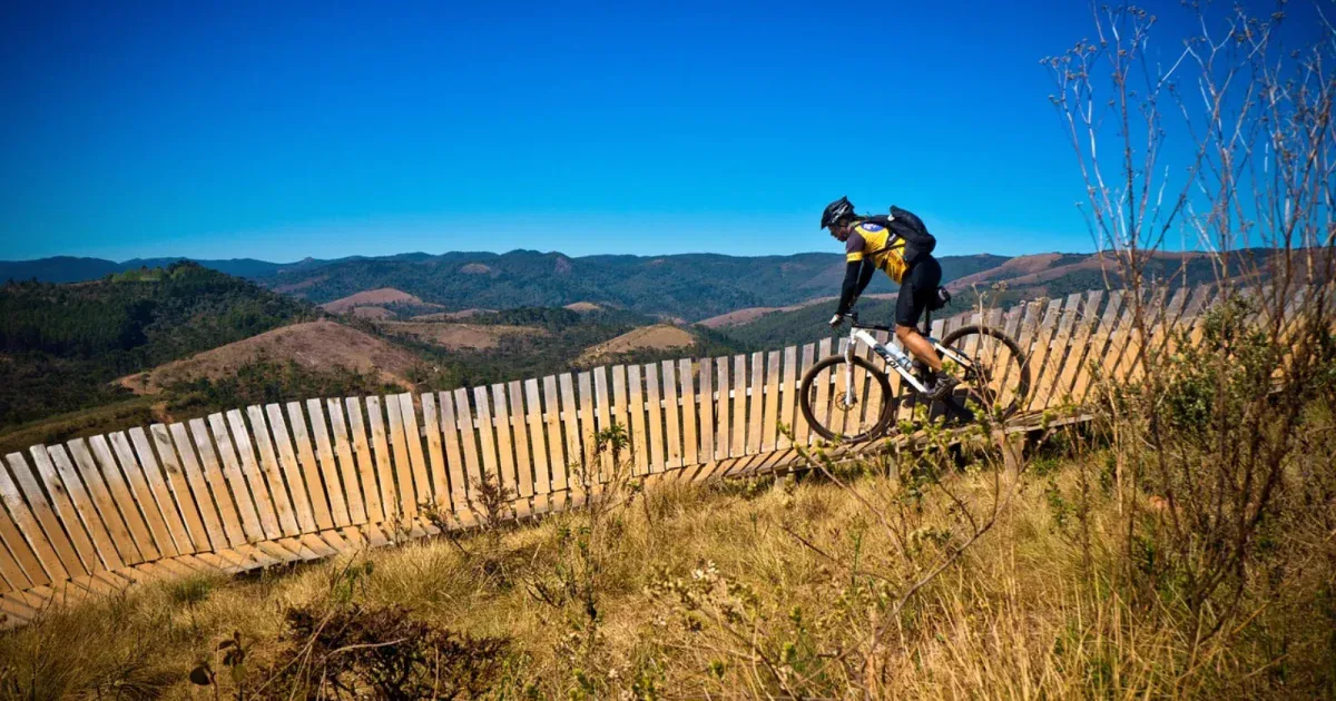 Rowerzysta MTB jedzie singletrackiem na zboczu góry przy drewnianym ogrodzeniu