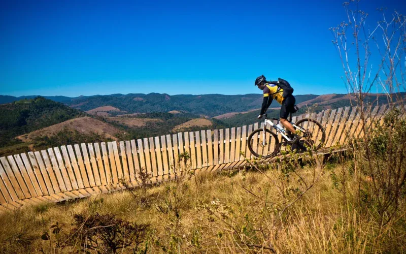 Rowerzysta MTB jedzie singletrackiem na zboczu góry przy drewnianym ogrodzeniu