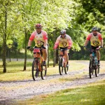 Grupa rowerzystów MTB jadąca leśną szutrową drogą