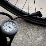 Pompka podłogowa z manometrem podpięta do wentyla koła rowerowego